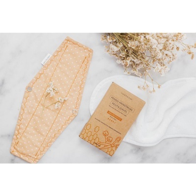 Pensos higiénicos reutilizáveis bege e branco com embalagem de papel castanho e flores secas