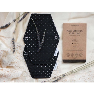 Absorvente menstrual reutilizável preto com pontos brancos e embalagem de papel reciclável castanho