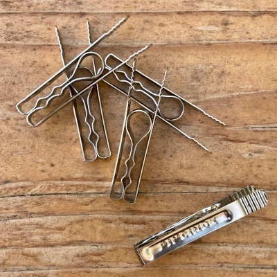 fixadores e clipe metálico sobre madeira clara