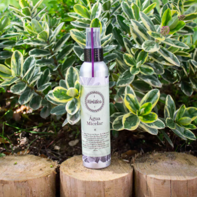 Frasco de Água Micelar Mawalibio sobre tronco de madeira com plantas ao fundo