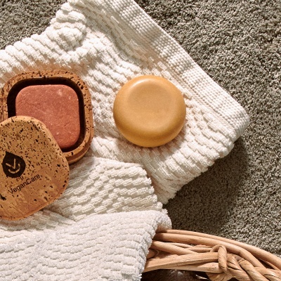 Sabonete VeganCare, pedra lisa e toalha branca numa cesta de vime