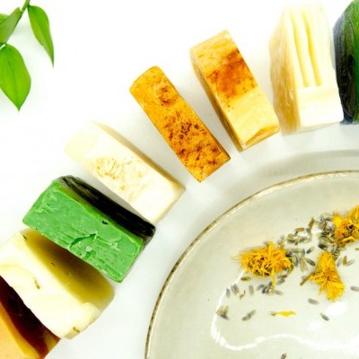 Sabonetes artesanais coloridos em meia-lua com folha verde e prato com flores secas