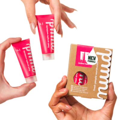 Desodorizantes naturais em tubos cor-de-rosa e embalagem castanha com texto, mãos femininas segurando.