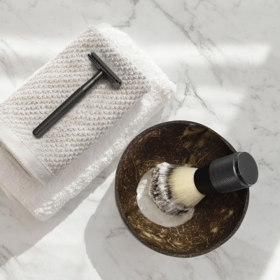 Utensílios para barbear com toalha branca sobre superfície marmorizada