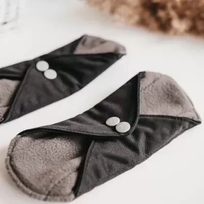 Pensos reutilizáveis cinzentos com botões brancos sobre superfície branca