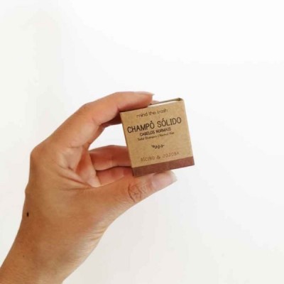 Mão a segurar embalagem pequena de champô sólido de cartão reciclável castanho claro