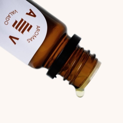 Garrafa âmbar com líquido a ser vertido e etiqueta com texto 'AROMAS VALADO AV'.