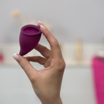 Copo menstrual roxo de silicone em mão feminina