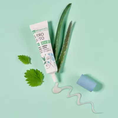 Tubo branco de gel com tampa azul, folhas verdes e gel em espiral sobre fundo verde-claro