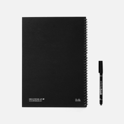 Caderno preto com capa dura e espiral, com caneta preta ao lado