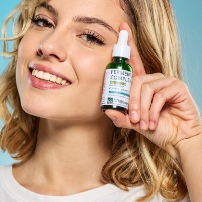 Mulher loira com frasco verde de produto orgânico com conta-gotas