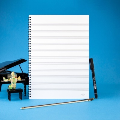 Caderno de pautas musicais com marcador preto e arco de violino ao lado de miniatura de piano e boneco de madeira