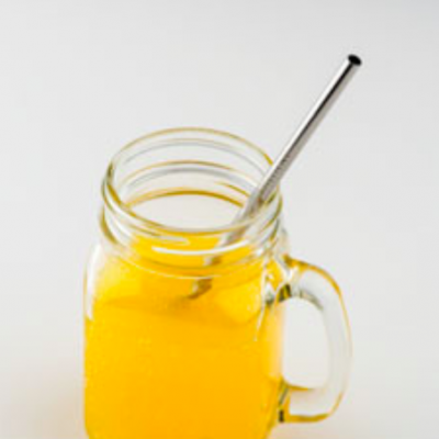 Jarro de vidro com líquido amarelo e canudo metálico