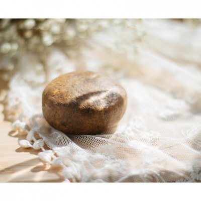 Pedra marrom sobre tecido de renda branca em superfície de madeira clara