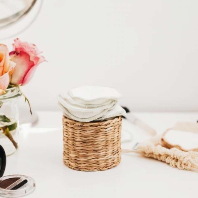 Cesta de palha com discos de algodão e flores cor de rosa ao lado