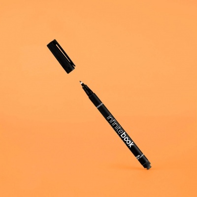 Caneta marcador preta com tampa sobre fundo laranja