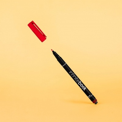 Marcador permanente vermelho com tampa removida sobre fundo amarelo