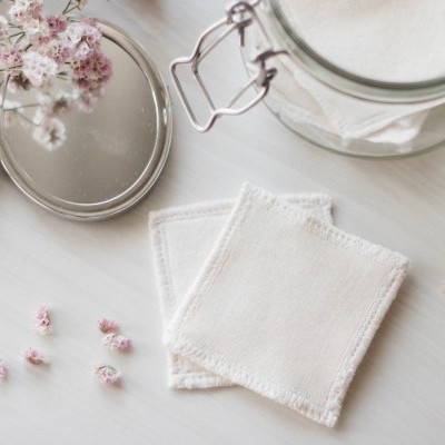 Três discos de algodão reutilizáveis brancos com frasco de vidro e flores secas