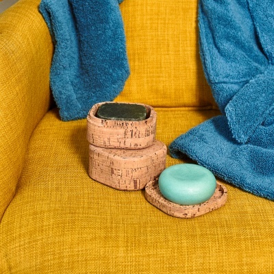 Sofá amarelo com toalhas azuis e recipientes em cortiça com sabonete azul