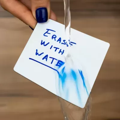 Cartão branco com texto escrito a azul e água a borrar o texto