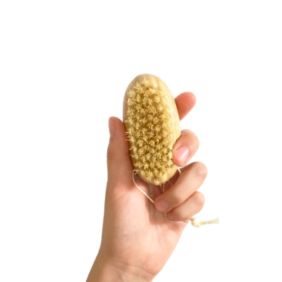 Escova de madeira pequena com cerdas claras segurada por uma mão