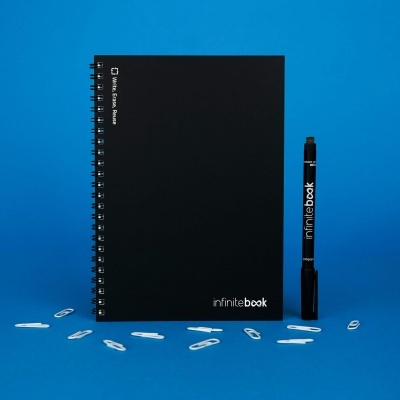 Caderno preto espiral e caneta preta com logo 'infinitebook' em fundo azul com clipes brancos ao redor