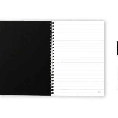 Caderno espiral aberto com capa preta e folhas pautadas, com caneta preta ao lado.