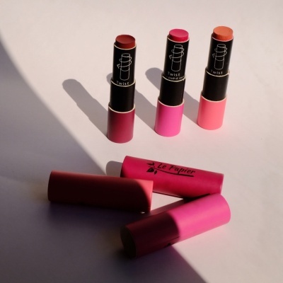 Três batons Twist com tampas coloridas e duas tampas removidas no chão