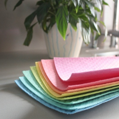 Conjunto de panos coloridos empilhados com planta ao fundo