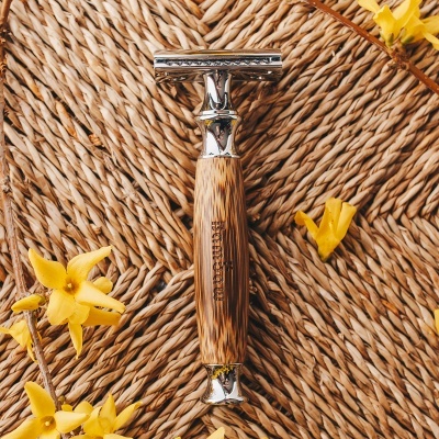 Barbeador clássico com cabo de madeira sobre superfície trançada e flores amarelas