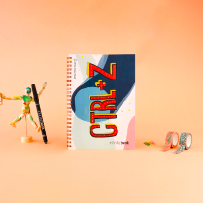 Caderno espiralado com capa azul, branca e rosa, texto vermelho CTRL + Z, boneco de madeira e fitas adesivas