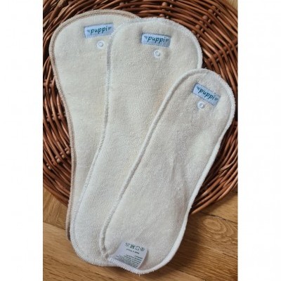 Absorventes de tecido reutilizáveis bege claro sobre cesto de verga castanha