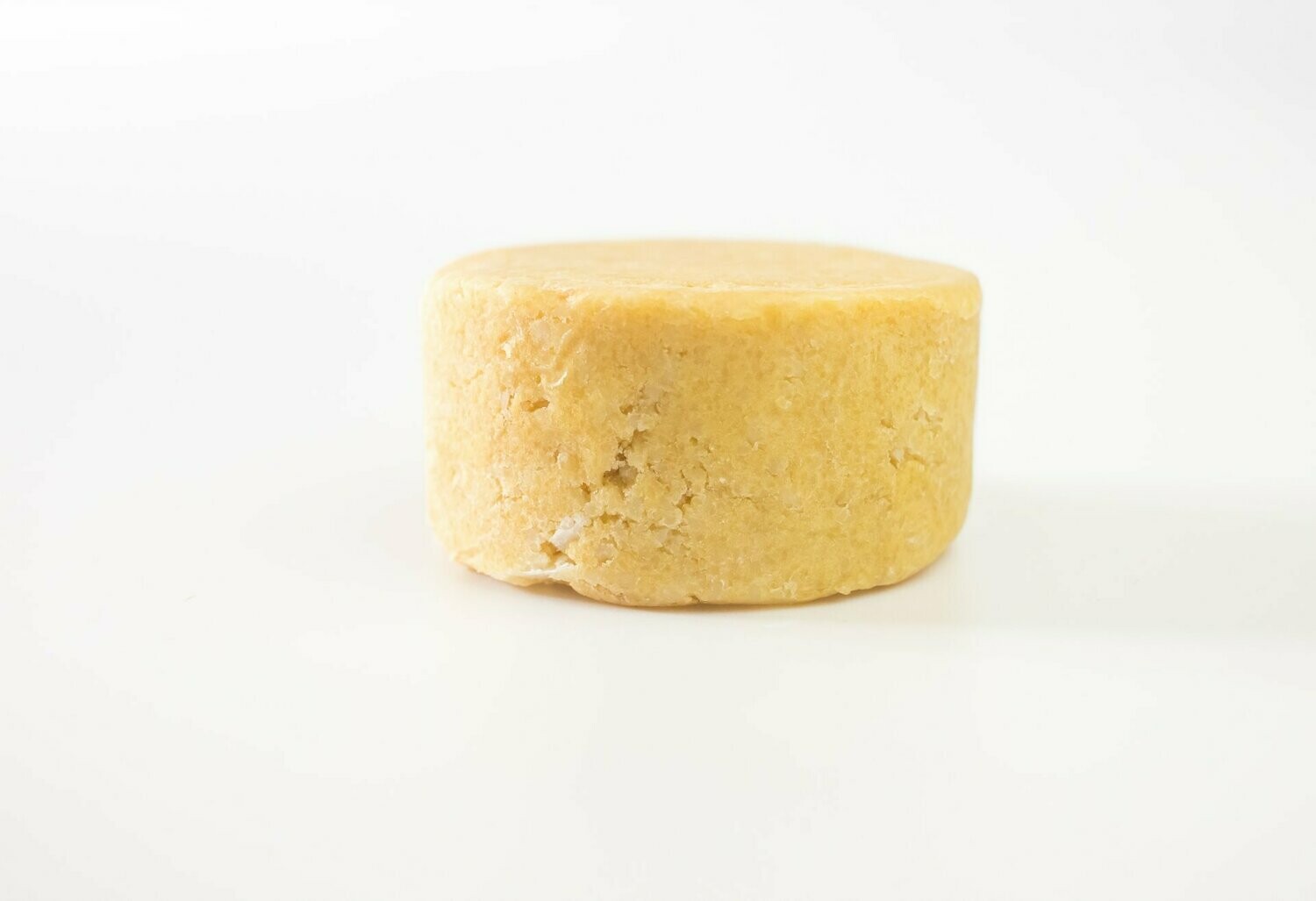 Champô Sólido Cabelos Secos Queijo redondo amarelo sobre fundo branco