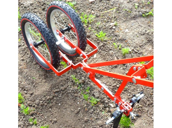 Enxada profissional com 2 rodas Acessório agrícola metálico vermelho com duas rodas de borracha pretas em solo de terra