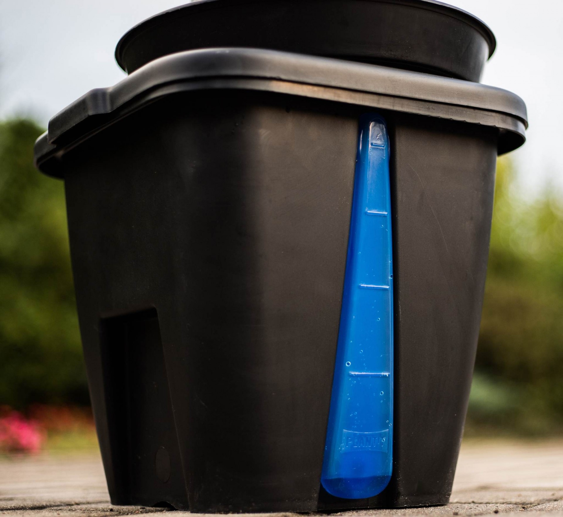 Torre Hidropónica Recipiente preto com garrafa azul ao ar livre