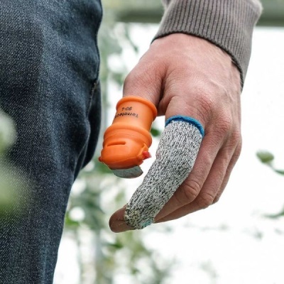 Mão com protetor de silicone laranja e luva de tecido cinza nos dedos, ao ar livre