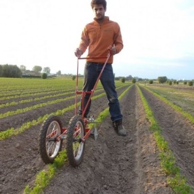 Homem usa ferramenta de agricultura manual vermelha em campo