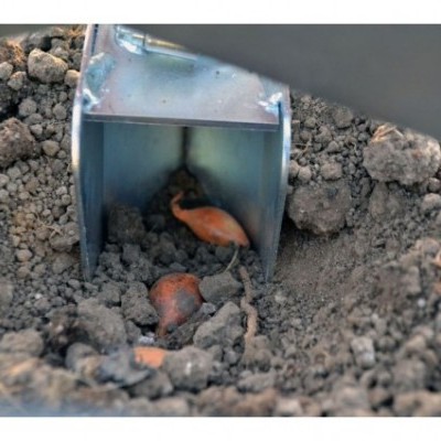 Mini escavadora metálica a cavar terra com raízes e pedras