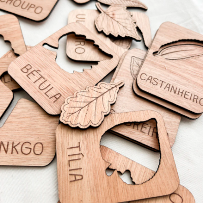 Etiquetas de madeira com recortes de folhas e nomes de árvores