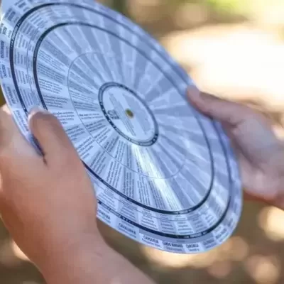 Mãos a segurar disco plástico com texto impresso em ambiente exterior