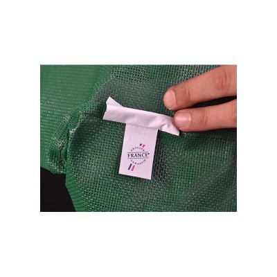 Etiqueta branca com texto Origine France Garantie numa malha verde sendo segurada por uma mão