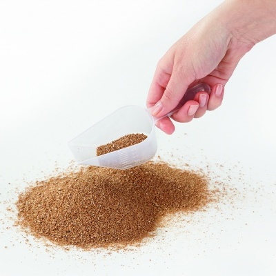 Concha branca a despejar pó marrom sobre mesa branca