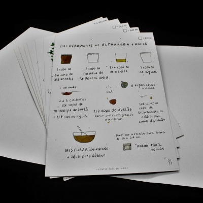 Folhas de papel com ilustrações e texto em português dentro de envelope branco aberto.