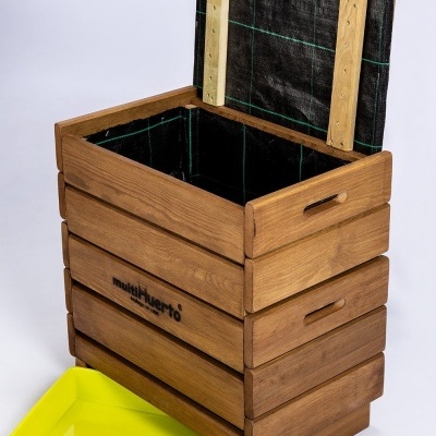 Caixa de madeira castanha com tampo aberto e revestimento interno preto, com uma bandeja amarela no chão ao lado.