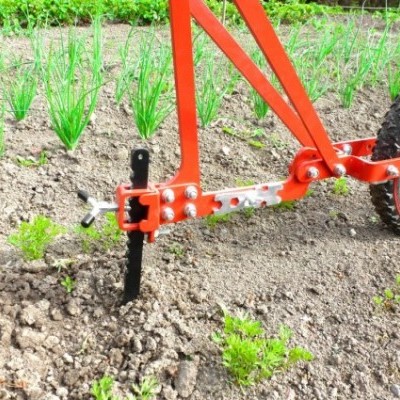Máquina agrícola vermelha com roda a trabalhar solo fértil e plantas verdes