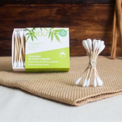 Embalagem de cotonetes de bambu e algodão da marca Babu sobre tecido bege