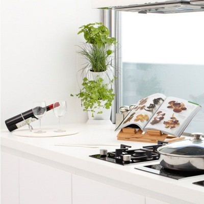 Bancada branca de cozinha moderna com suporte de livro, plantas aromáticas, vinho e fogão a gás