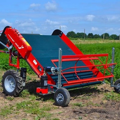 Máquina agrícola vermelha com correia verde em campo aberto