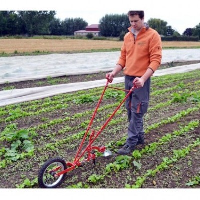Homem a usar carrinho manual metálico vermelho com duas rodas numa plantação