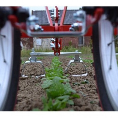 Máquina agrícola metálica a cultivar solo entre plantas verdes